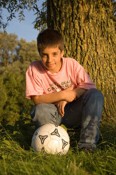 boy kneeling by a soccer ball