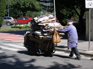 alter mann beim transport von kartons altpapier