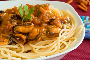 white bowl with spaghetti on tomato seafood sauce and mussel