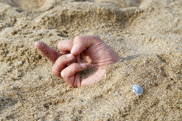 main enterré dans le sable