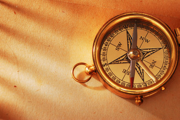 Antique brass compass over old background