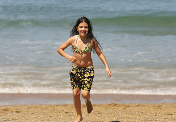 petite fille en maillot de bain qui court sur la plage