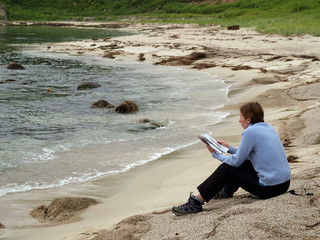 girl reading magazine on the wild beach