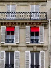 Fototapeta na wymiar Façade de paris, stores rouges et volets blancs.