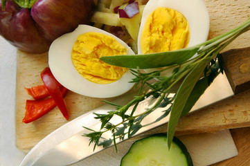 Egg, herbs on knife and other salad ingredients