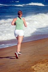 Photo of Young woman running alone on the beach.