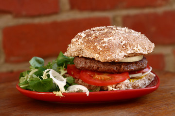 beef hamburger on a wholemeal bun with onion, tomato and salad