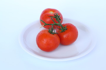 Three tomatos on a white plate