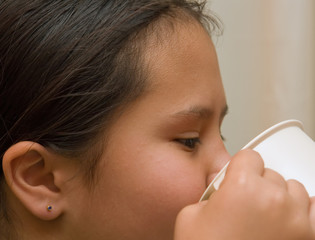 young girl drinking from cup close up