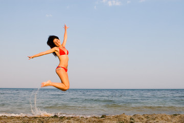happy young woman is jumping in beach