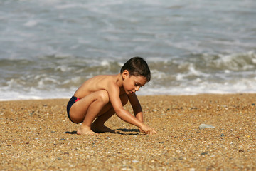 petit garçon qui cherche dans le sable