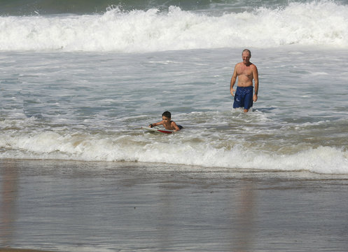 petit garçon qui fait du bodyboard avec son père