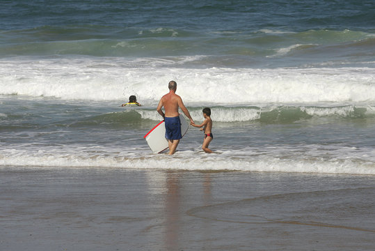 petit garçon qui fait du bodyboard avec son père