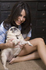 Young woman playing with her pug.