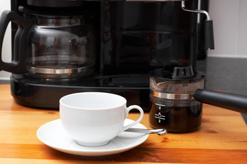 Closeup of white coffee cup next to coffee machine