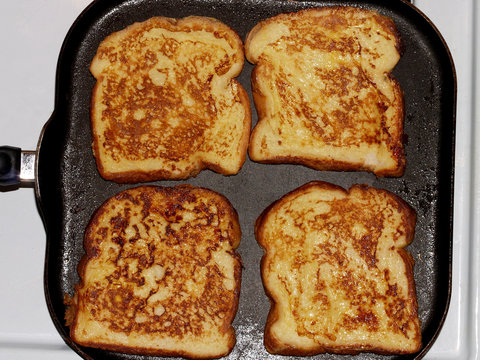 Four Slices Of French Toast Cooking On Griddle