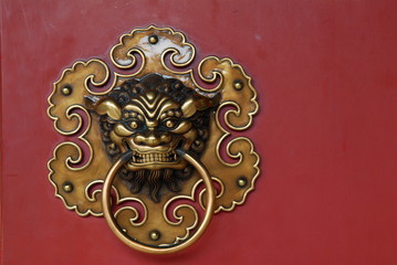 bronze lions head on the red doors
