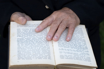 Naklejka premium Senior's hands on old book