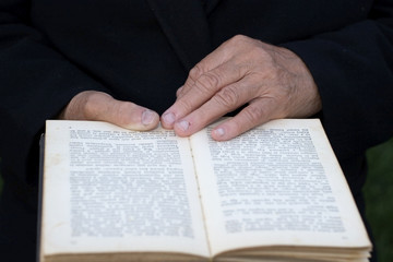 Naklejka premium Senior's hands on old book