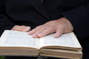 Senior's hands on old book