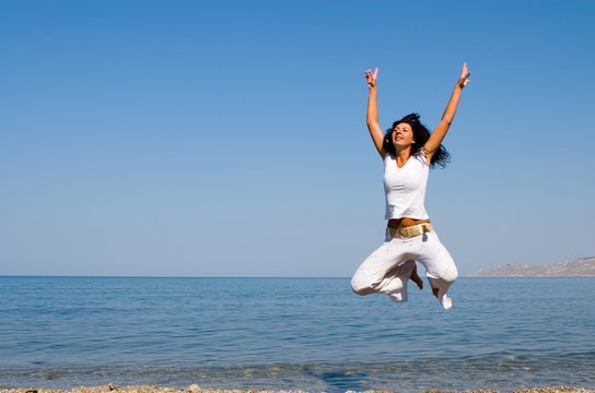 happy young woman is jumping in the beach