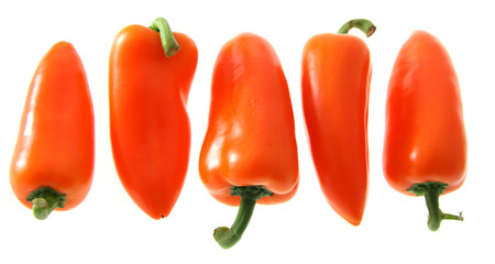 five small orange bell pointed peppers in row