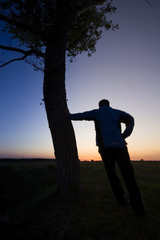 A man's silhouette in the sunset with a tree