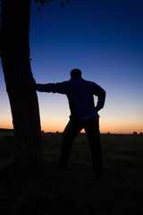 A man's silhouette in the sunset with a tree