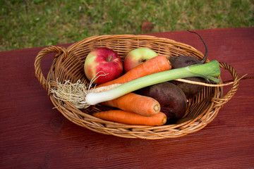 Apples and vegetables in a basket with wood texture background