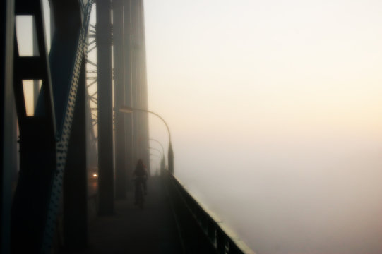 Cyclist is travelling on the foggy bridge