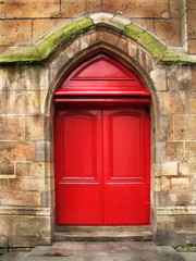 Fototapeta na wymiar Czerwone drzwi starej katedry z kamienia
