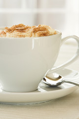 A side view image of a cup of Cappuccino in a white cup.