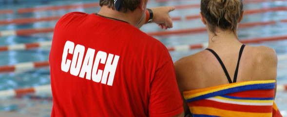 A coach, giving instruction to a young female swimmer