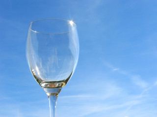 Empty wineglass on sky background
