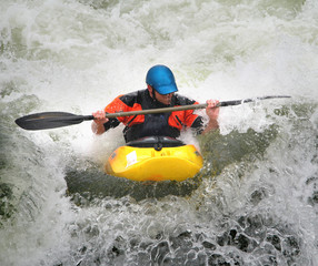 Fototapeta na wymiar Człowiek wiosłowaniu jego Kayak na Whitewater Rapids