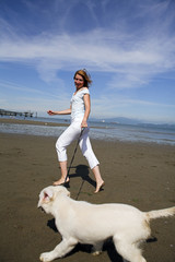 woman running with her dog on the beach