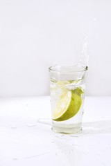  piece of orange splashing on glass of water isolated