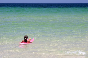Young girl on pink air-bed in the sea