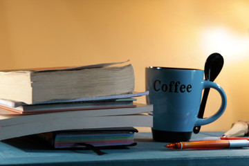 blue cup of coffee with books and pens