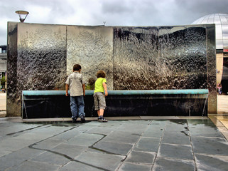 Two boys playing by steel water feature