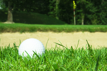 Golf ball in front of green bunker