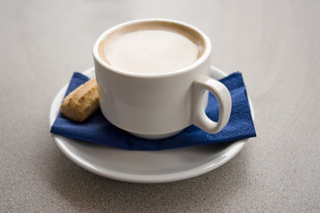 flat white coffee with biscotti on blue napkin close up