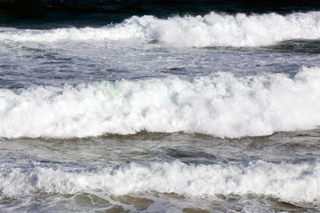 Three sets of white surf rolling in