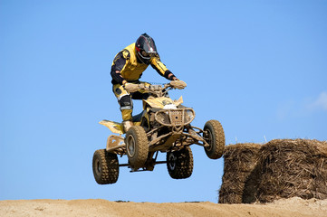 Teenager on a yellow quad bike jumping