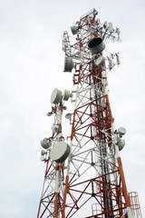 two cellular communication towers on a cloudy day