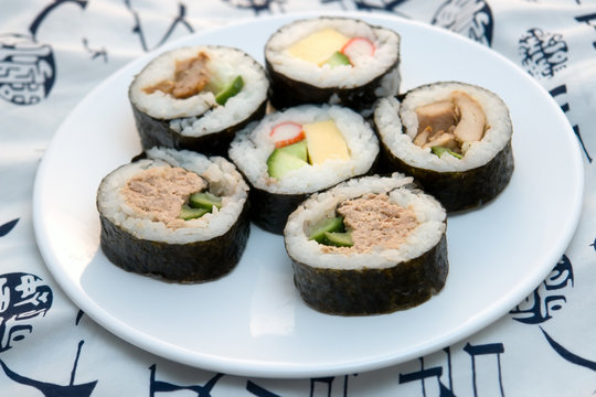 sushi rolls on round plate on white kimono background