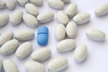 Fototapeta na wymiar Niebieskie tabletki pigułka wśród szarych