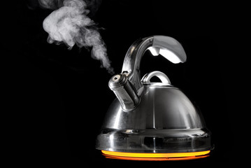 Tea kettle with boiling water on black background