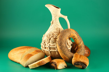 Bread and a jug on a green background.