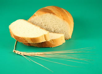 A long loaf of bread and an ear on a green background.